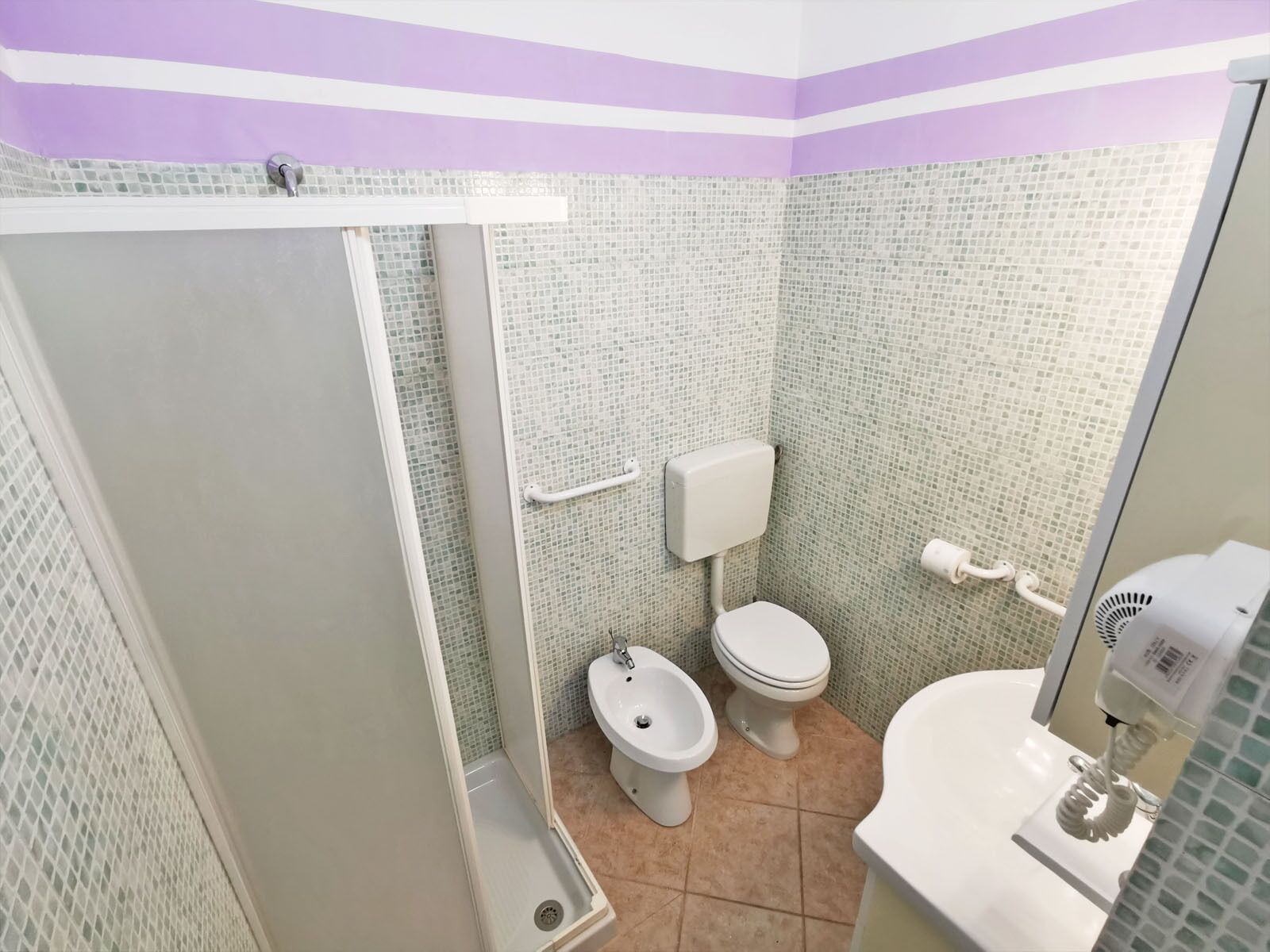 Une salle de bain équipée d’une douche, de toilettes, d’un bidet et d’un lavabo.