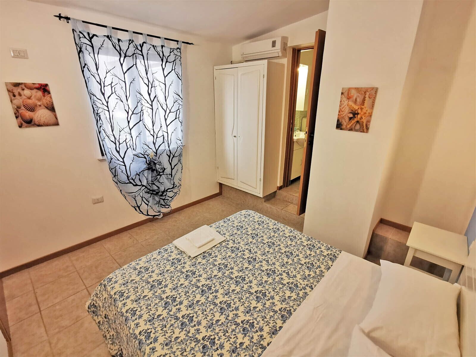 A bedroom with a bed, a wardrobe, and a bathroom visible through an open door.