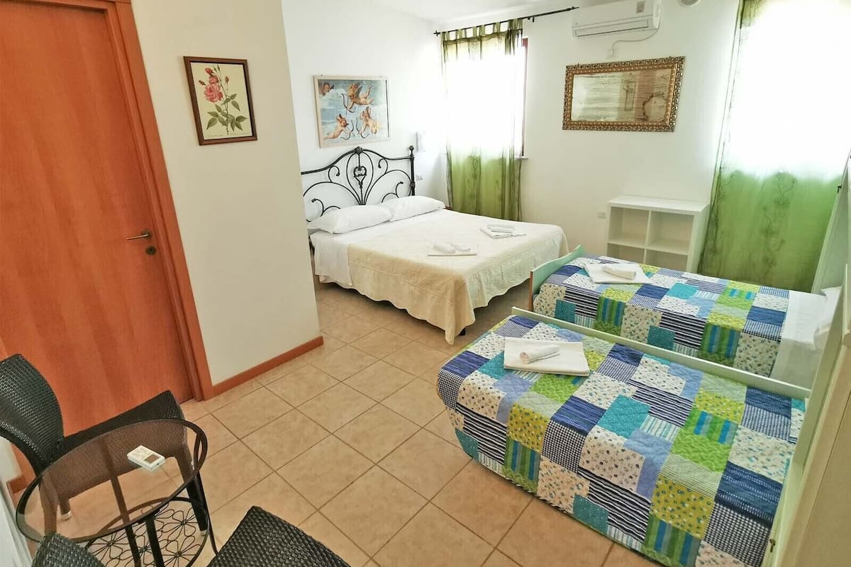 A room with two beds, a chair, a small table, and a mirror.