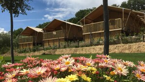 A row of wooden cabins with balconies, surrounded by a grassy area with pink and yellow flowers. - Il Girasole (Massignano)