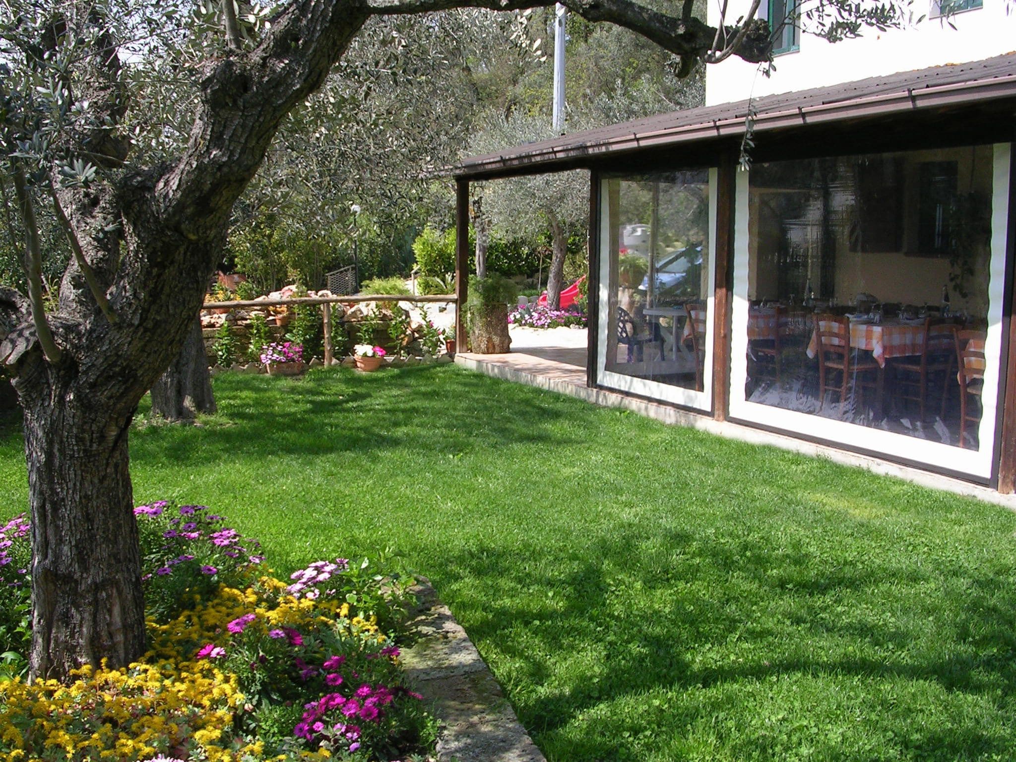 A well-maintained garden with a lawn, flowering plants, and a pergola structure.