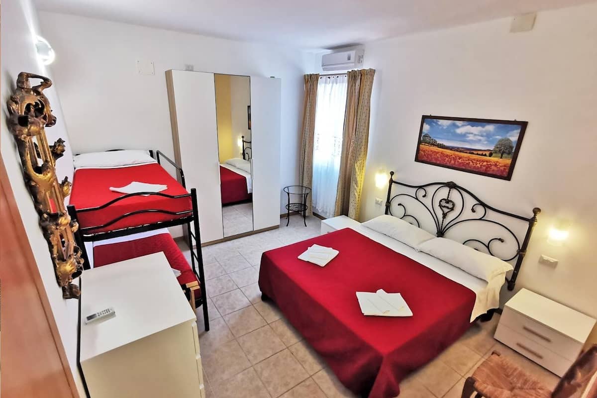 A hotel room with two beds, a desk, a chair, a small table, and a painting on the wall.
