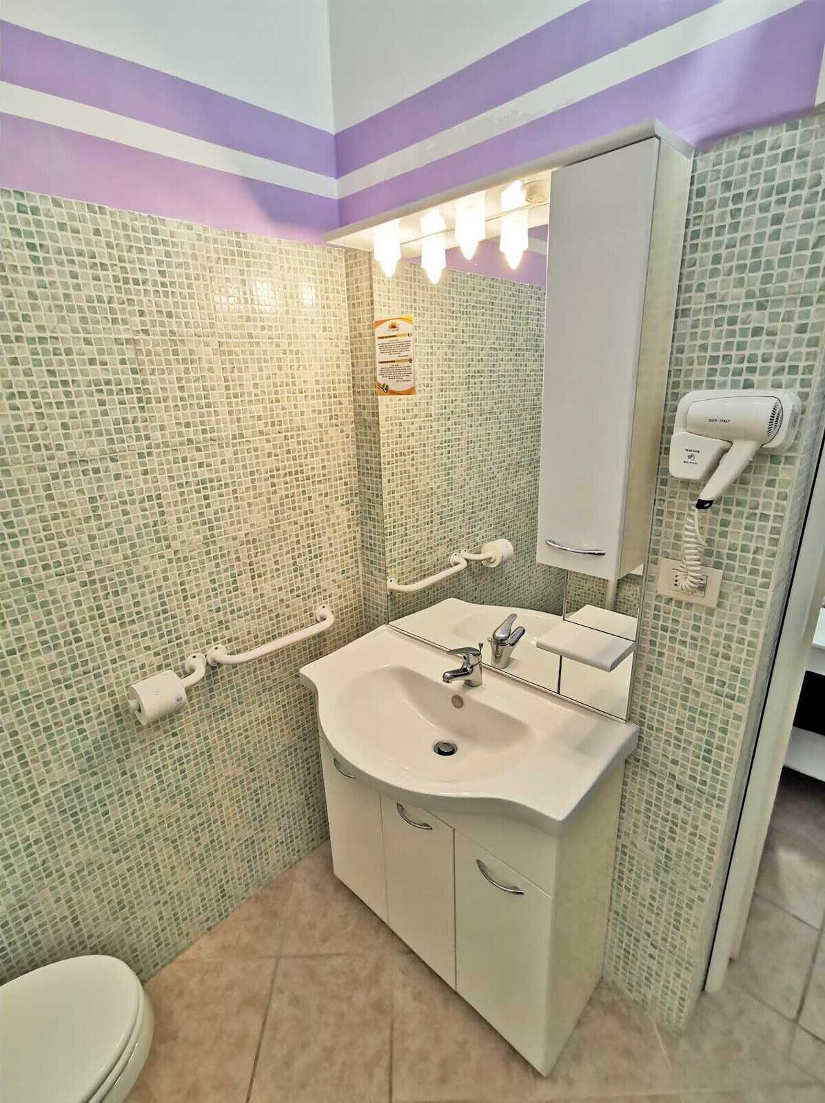 Un baño con lavabo, espejo y secamanos.