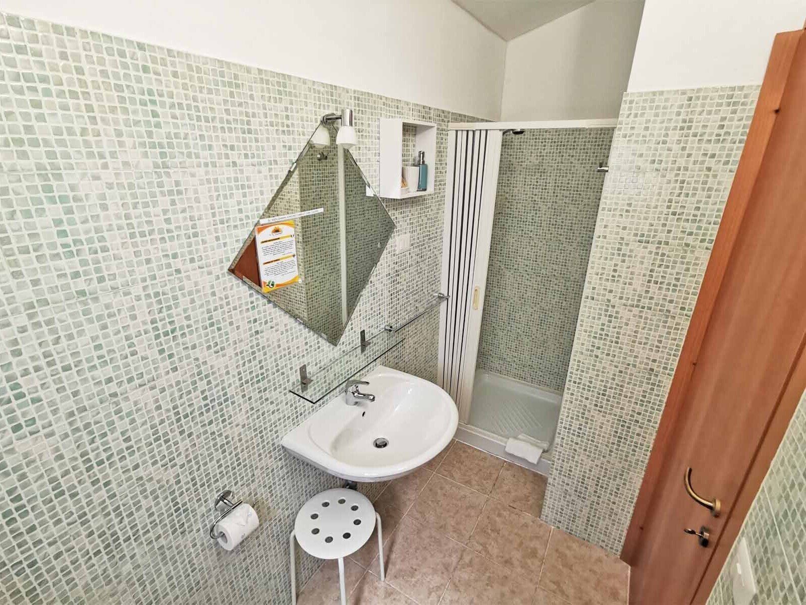 Ein Badezimmer mit einem weißen Waschbecken, einem Spiegel und einer Duschkabine.