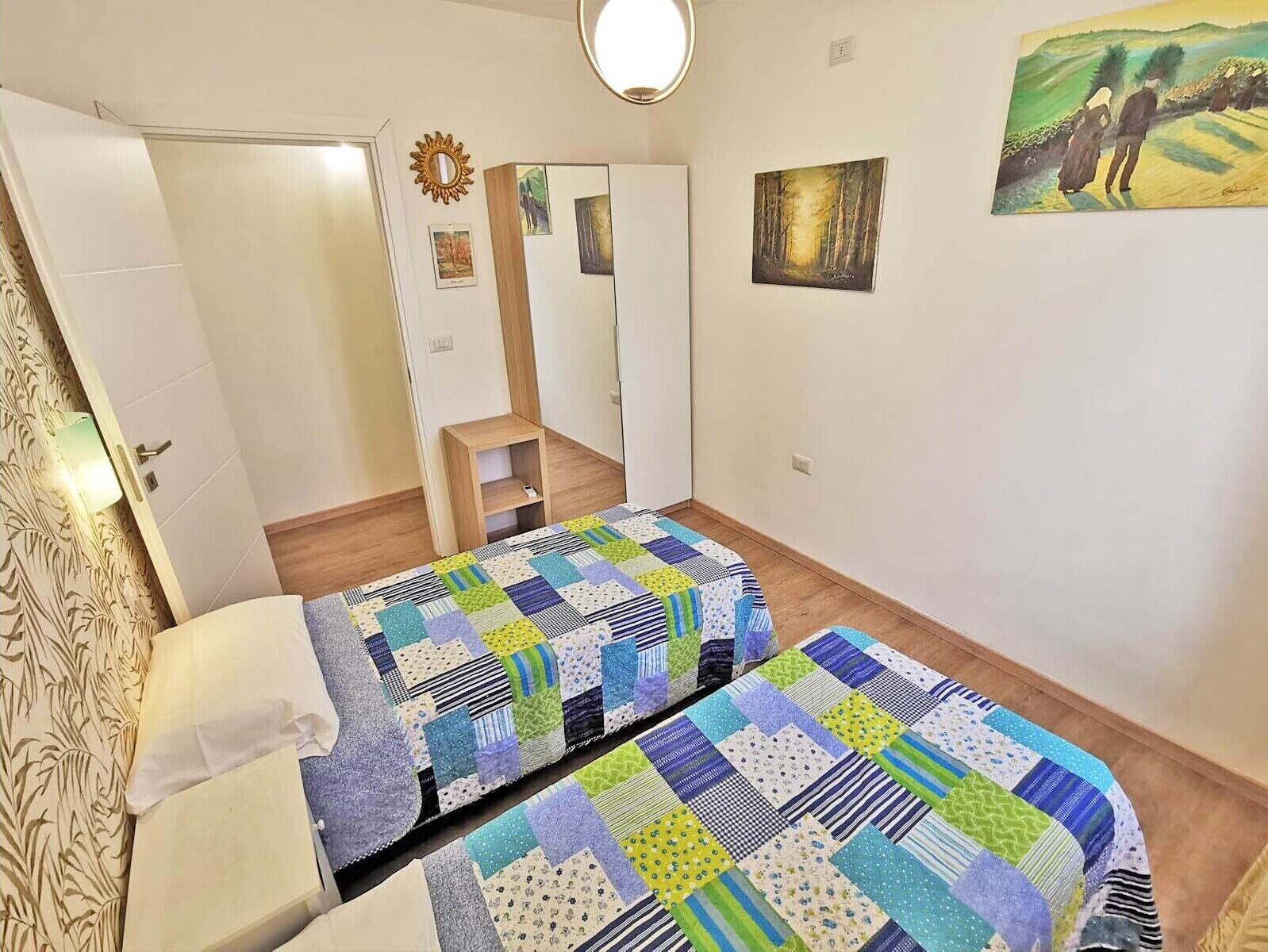 Een kamer met twee bedden, een spiegel en een klein houten plankje.