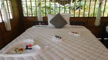 A bed with a quilted white bedspread, two pillows, and a decorative arrangement of flowers on the bed.