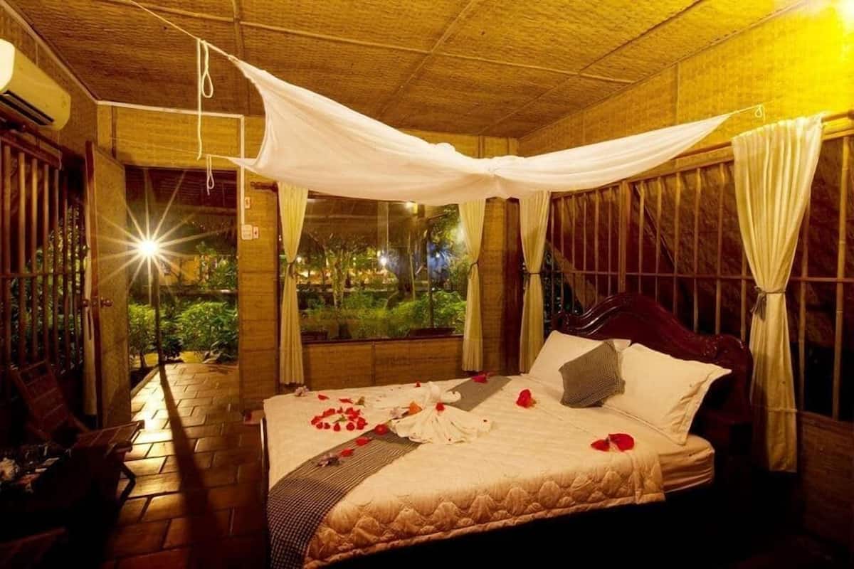 A room with a bed, a window, and a view of greenery outside.