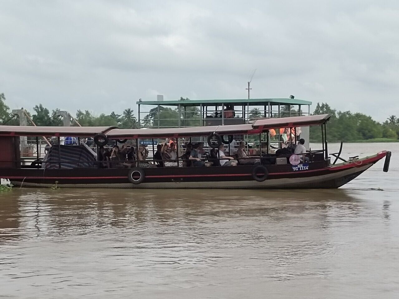 Un barco con cubierta techada y pasajeros.