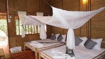 A room with two beds, each with a canopy, and a brick floor.