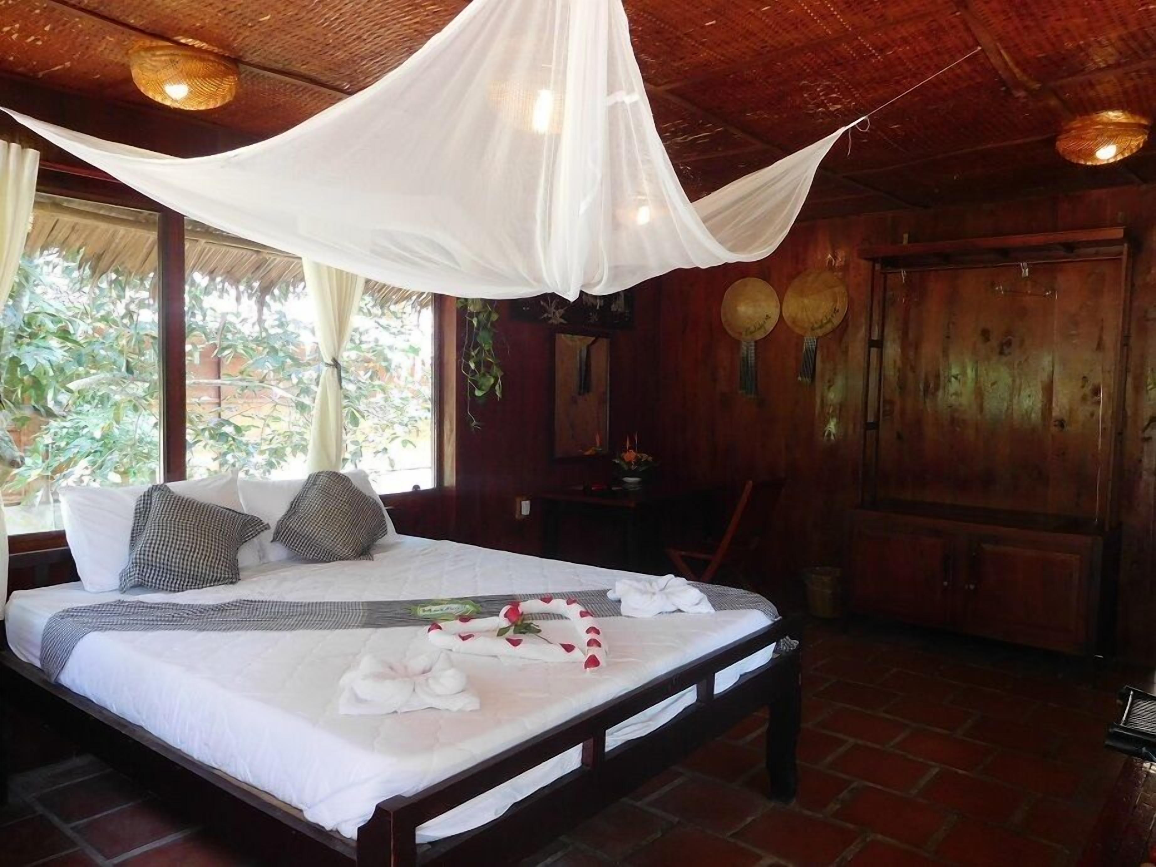 A room with a bed, a wooden wardrobe, and a window with curtains.