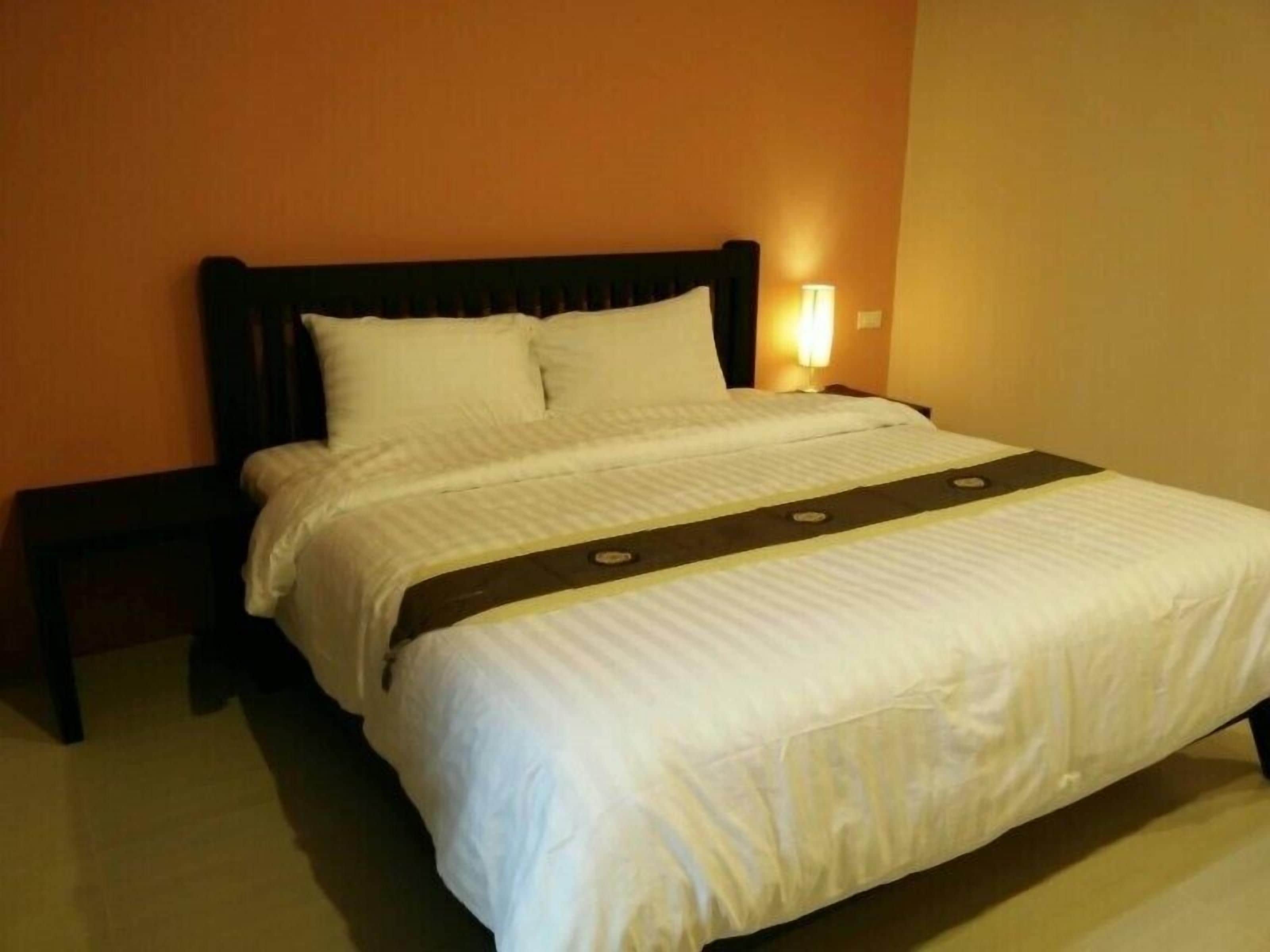 A hotel room with a bed, a nightstand, and a wall-mounted lamp.