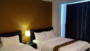 A hotel room with two beds, a nightstand with a lamp, and a window with curtains. - One Fu Hotel (Surin)