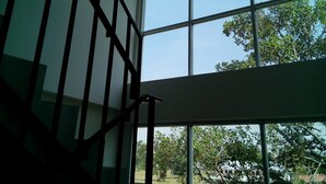 A staircase with metal railings leading to a large window with multiple panes. - One Fu Hotel (Surin)
