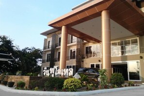 A multi-story hotel with a modern design, featuring a prominent entrance with large columns and a covered area.