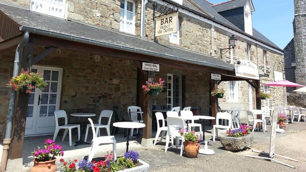 A stone building with outdoor seating and a sign for a bar and hotel. - Hotel du Tertre (Mont-Dol)