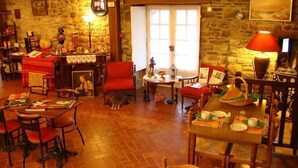 A cozy room with stone walls, a fireplace, and a dining area with a table set for two. - Hotel du Tertre (Mont-Dol)