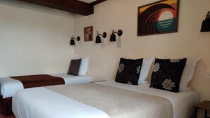 A hotel room with two beds, each with white bedding and black floral pillows. There are wall-mounted lamps and a painting of a sunset. - Hotel du Tertre (Mont-Dol)