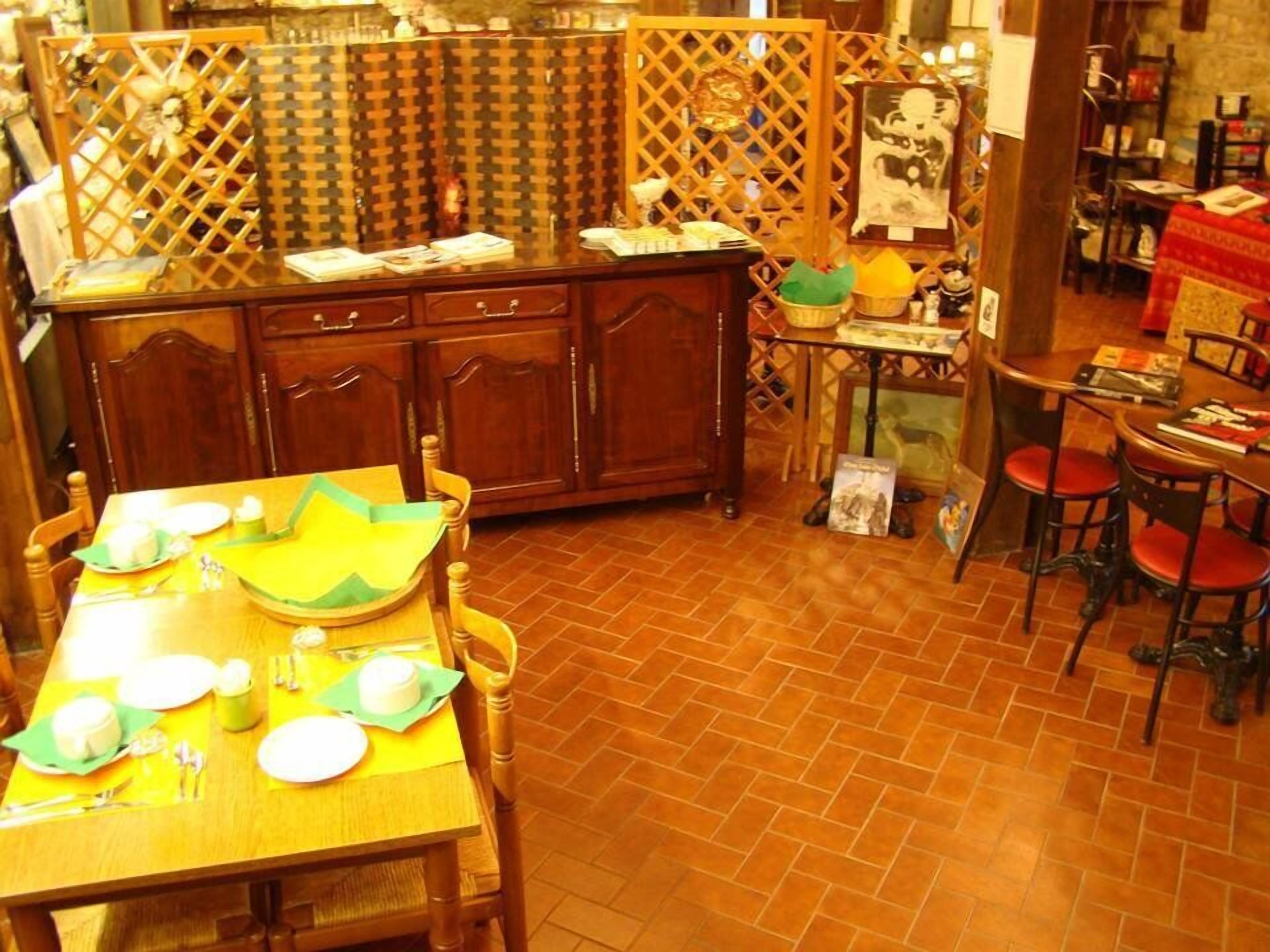 A dining area with a wooden table set for four, a kitchen area with wooden cabinets, and a small table with books and a basket.