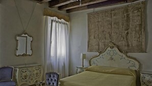 Ein Zimmer mit einem Bett, einem Sessel, einem Schminktisch und einem Spiegel.