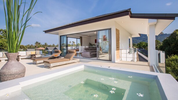 A modern house with a glass-enclosed living area, a hot tub, and a view of the mountains. -  Ban Tai Estate Villas (Koh Samui)