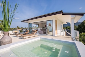 A modern house with a glass-enclosed living area, a hot tub, and a view of the mountains. -  Ban Tai Estate Villas (Koh Samui)