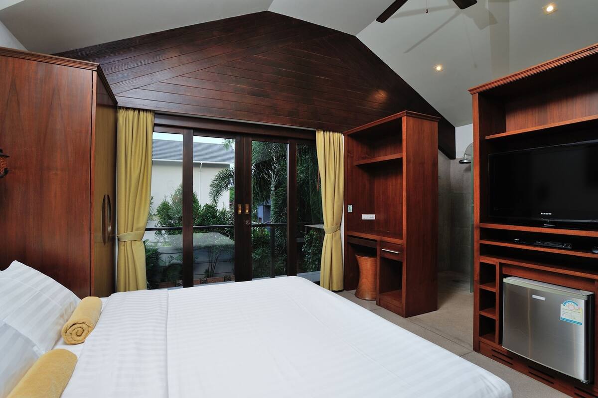 Une chambre d’hôtel avec un lit, des armoires en bois, une télévision et un petit réfrigérateur.