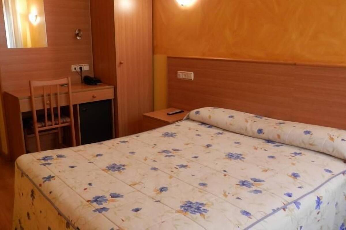 Una habitación pequeña con cama, escritorio y silla.