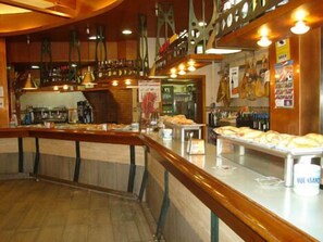 A bar area with a counter displaying pastries and bottles.