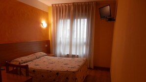 A hotel room with a bed, a desk, a chair, a television, and a window with curtains. - Hotel Doña María (Gijon)