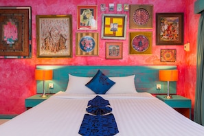 A bed with white linens, two nightstands with lamps, a teal headboard, and various framed artworks on the wall. - Barefoot Hotel Kalim Beach Front (Patong)
