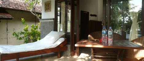 A room with a bed, a table with chairs, and a window with curtains.