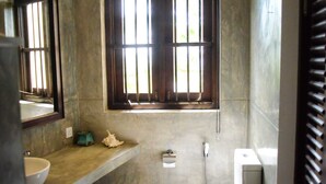 Ein Badezimmer mit Fenster, Waschbecken, Toilette und Spiegel.