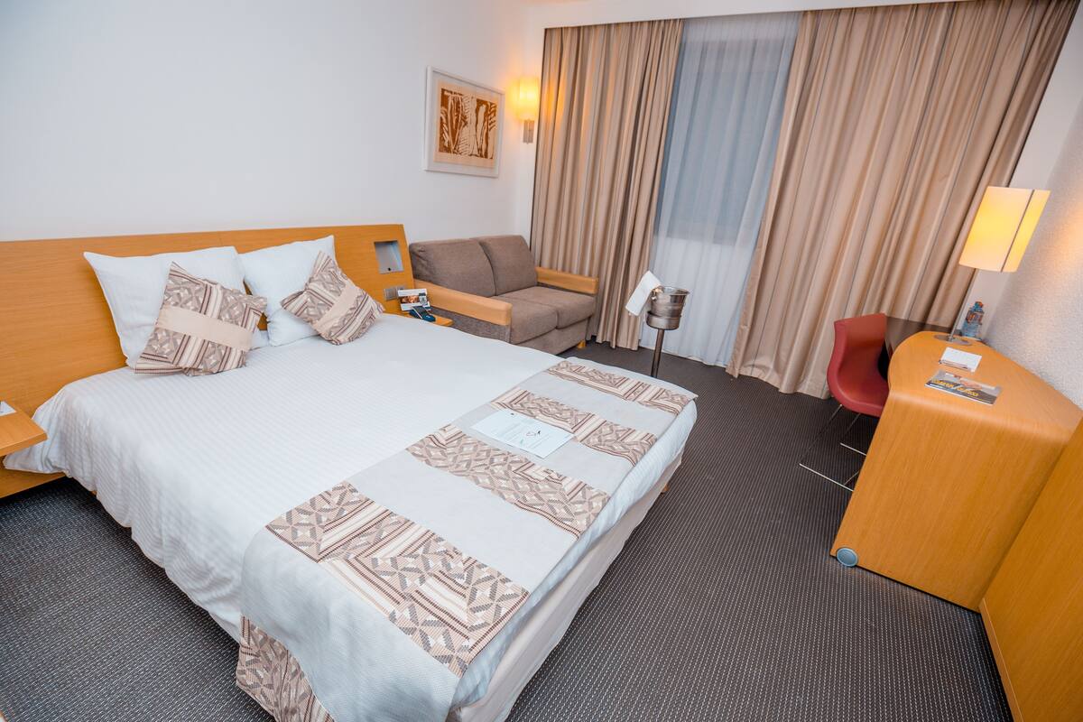 Una habitación de hotel con una cama grande, un sofá, un escritorio y una silla.