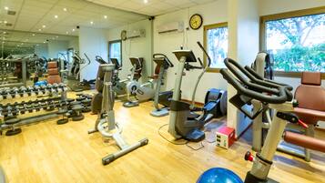 Un gimnasio con diversos equipos de ejercicio, como cintas de correr, bicicletas estáticas y pesas sueltas.