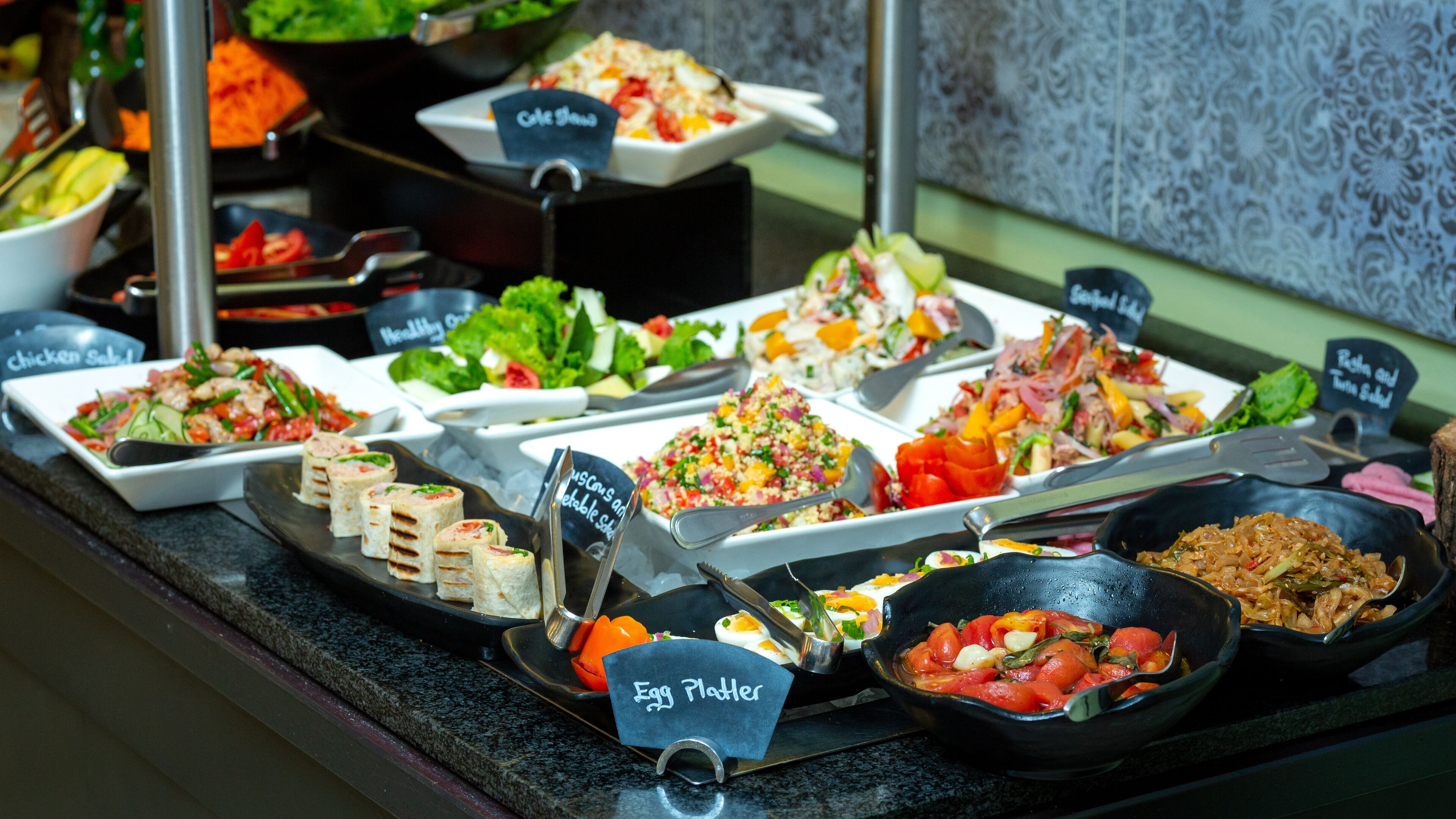 A buffet with various dishes including salads, egg platters, and rice dishes.