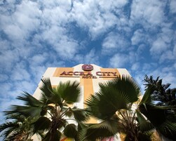 The exterior of the Accra City Hotel with a clear sky and palm trees in the foreground.
