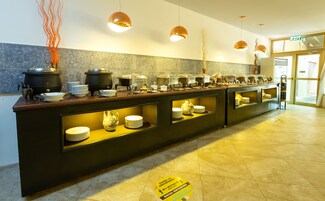A buffet setup with multiple serving stations, a coffee station, and a decorative vase.