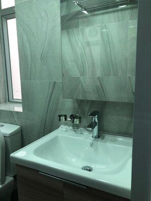 Bathroom features a sleek sink, chrome faucet, and large rectangular tiles.