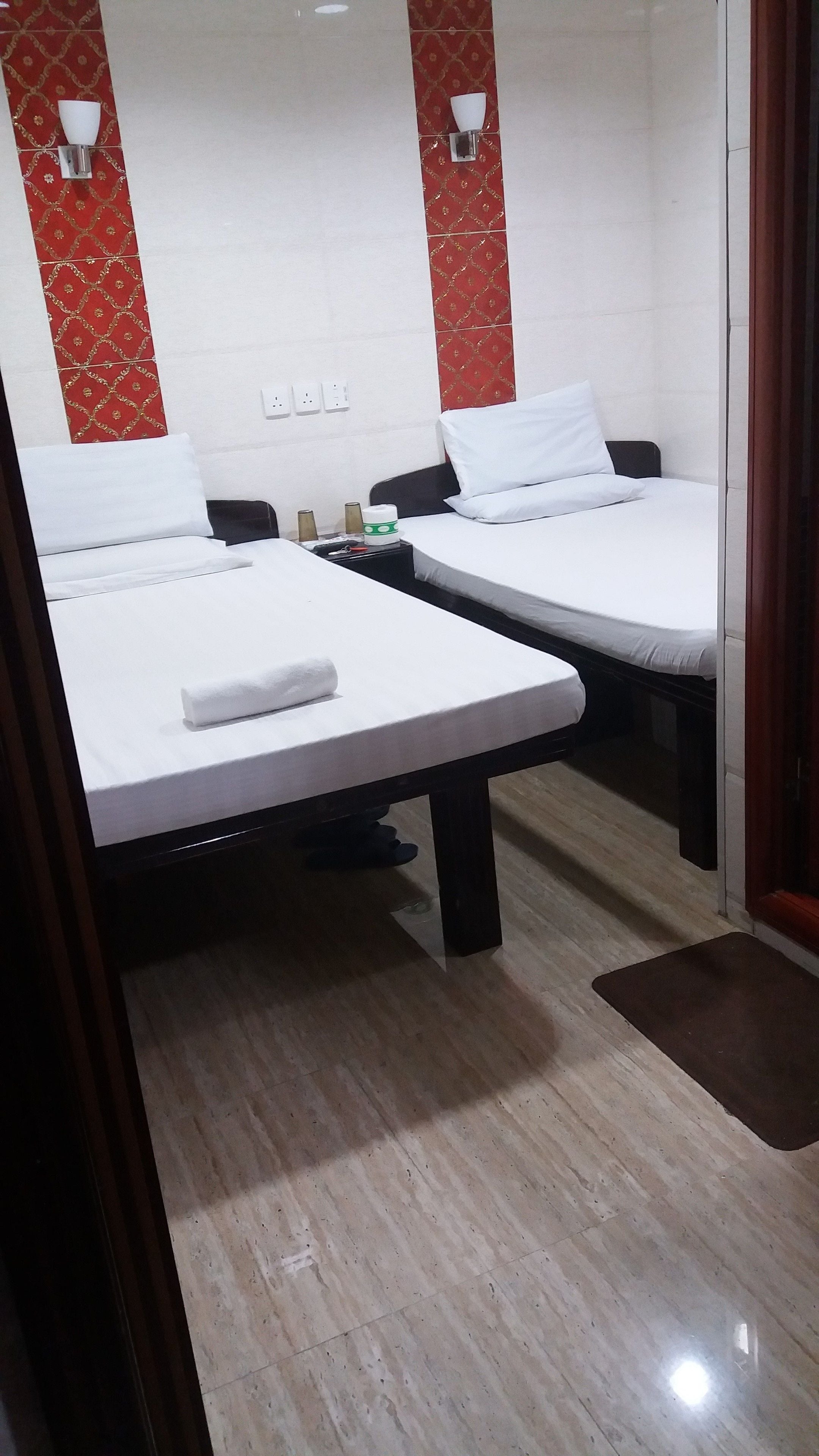 A hotel room with two beds, a small table, and a nightstand.