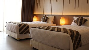 A hotel room with two beds, a large window with curtains, a wall with vertical wooden slats, and a lamp on each bed. - Grand Laguna Hotel & Villa (Colomadu)