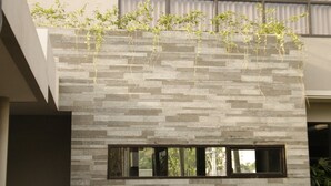 A modern building with a stone facade and a window. - Grand Laguna Hotel & Villa (Colomadu)
