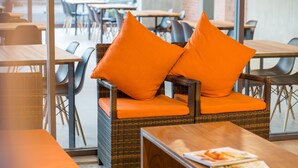 A wicker chair with orange cushions and a wooden table with a magazine. - B2 Udon Boutique & Budget Hotel (Udon Thani)