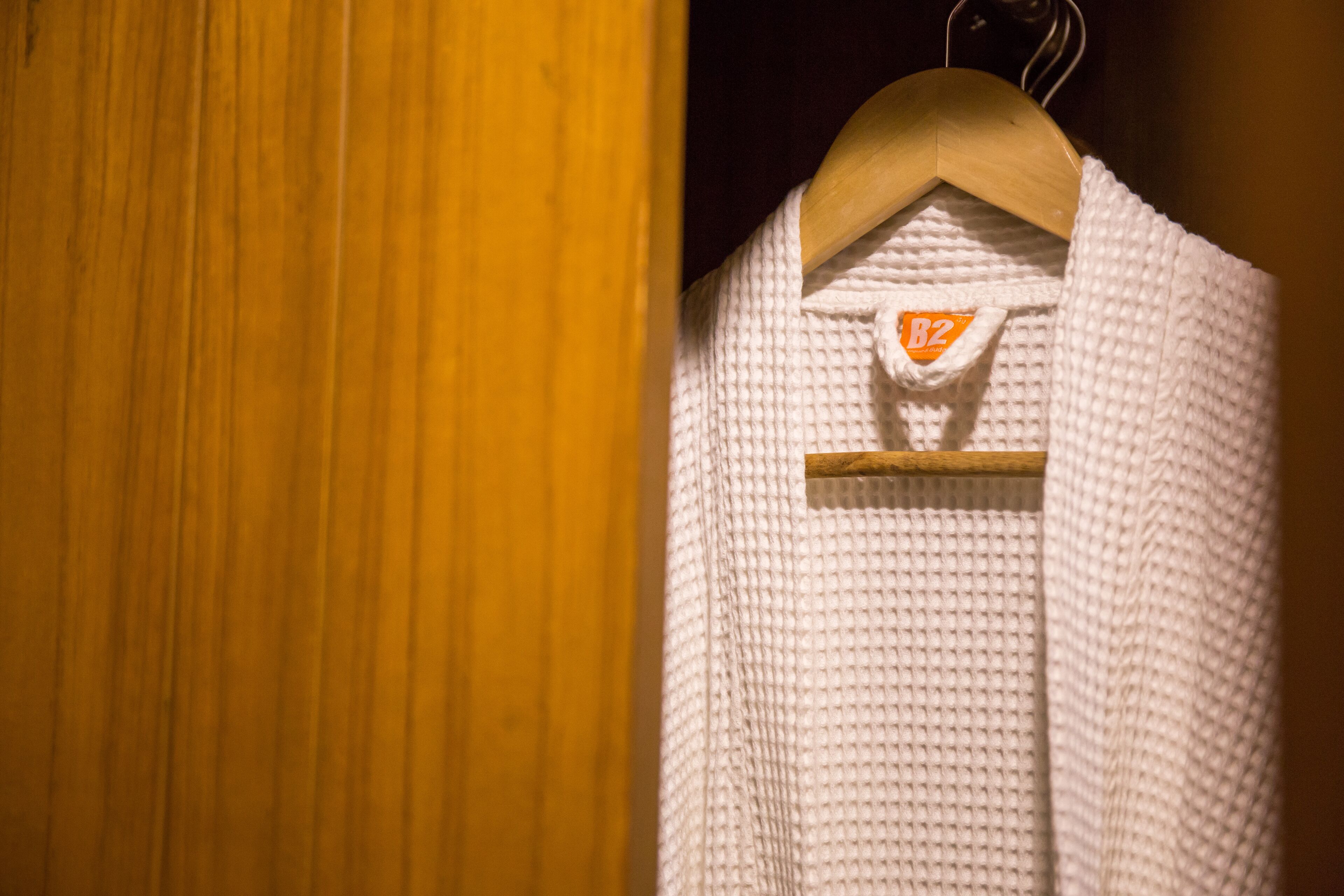 A white knitted garment hanging on a wooden hanger with a tag labeled "B2".