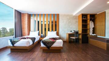 A modern hotel room with two beds, a wooden wardrobe, a desk, and a large window.