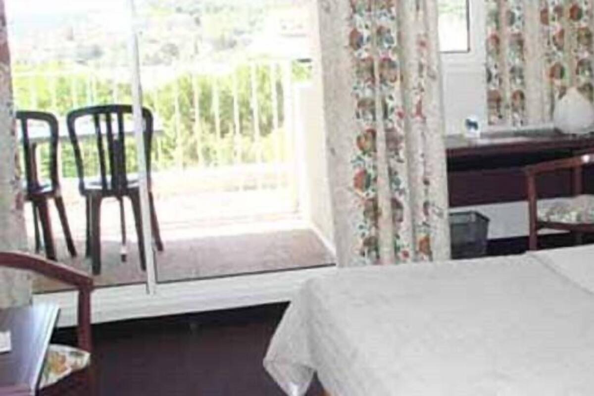 Une chambre d’hôtel avec un lit, un bureau et une chaise. Il y a une fenêtre avec des rideaux.