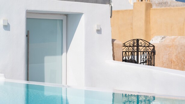 A poolside view of a building with a blue dome and a white door. - White Concept Caves (Santorini)