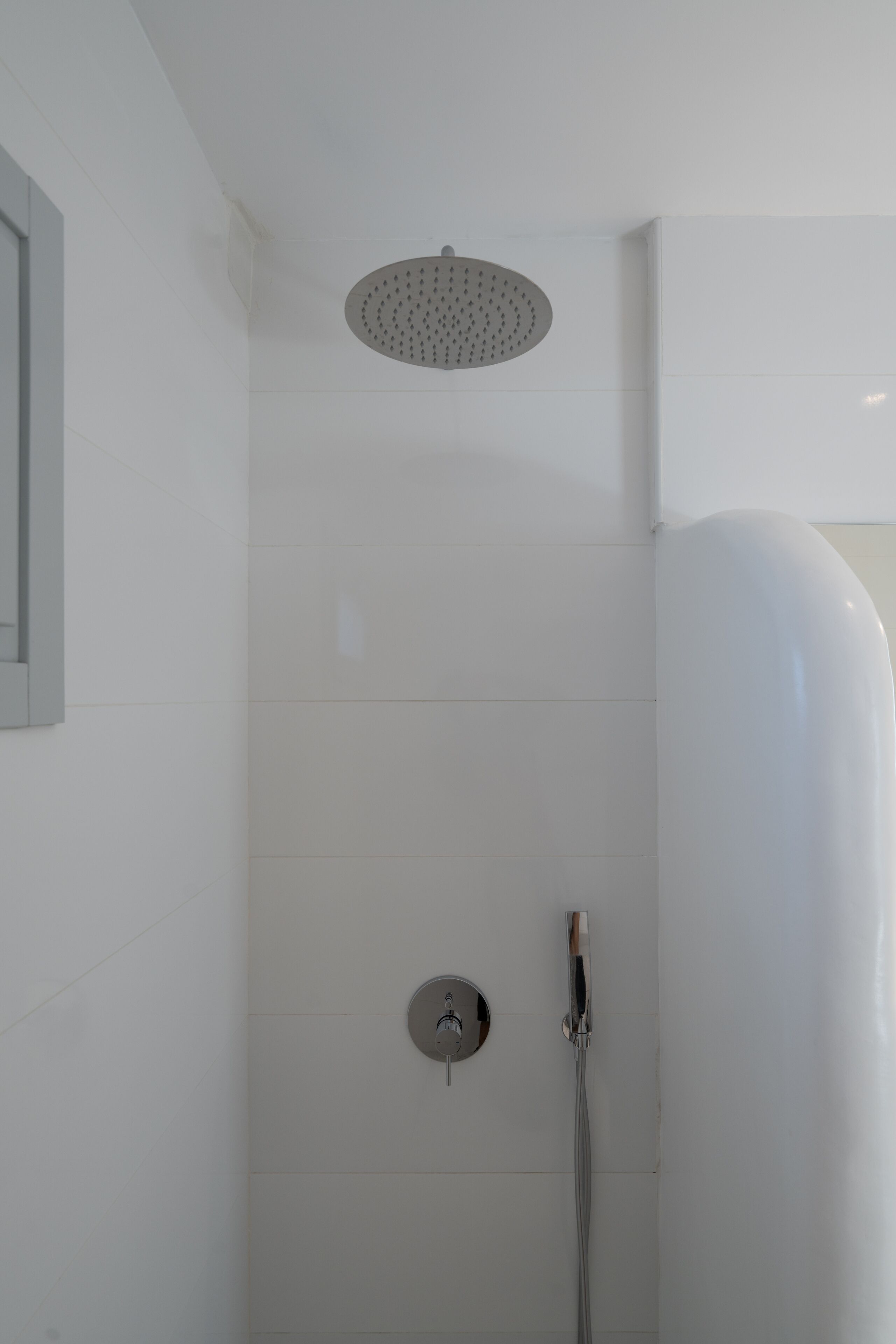 Een moderne douche met een regendouchekop en een handdouche.