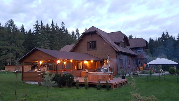 A large wooden house with a covered deck and a hot tub. - Penzion Sileo (Pribylina)