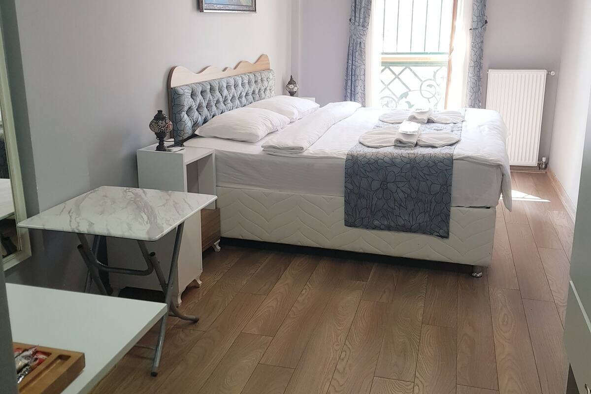 A neatly arranged bedroom with a bed, bedside table, and a small desk.