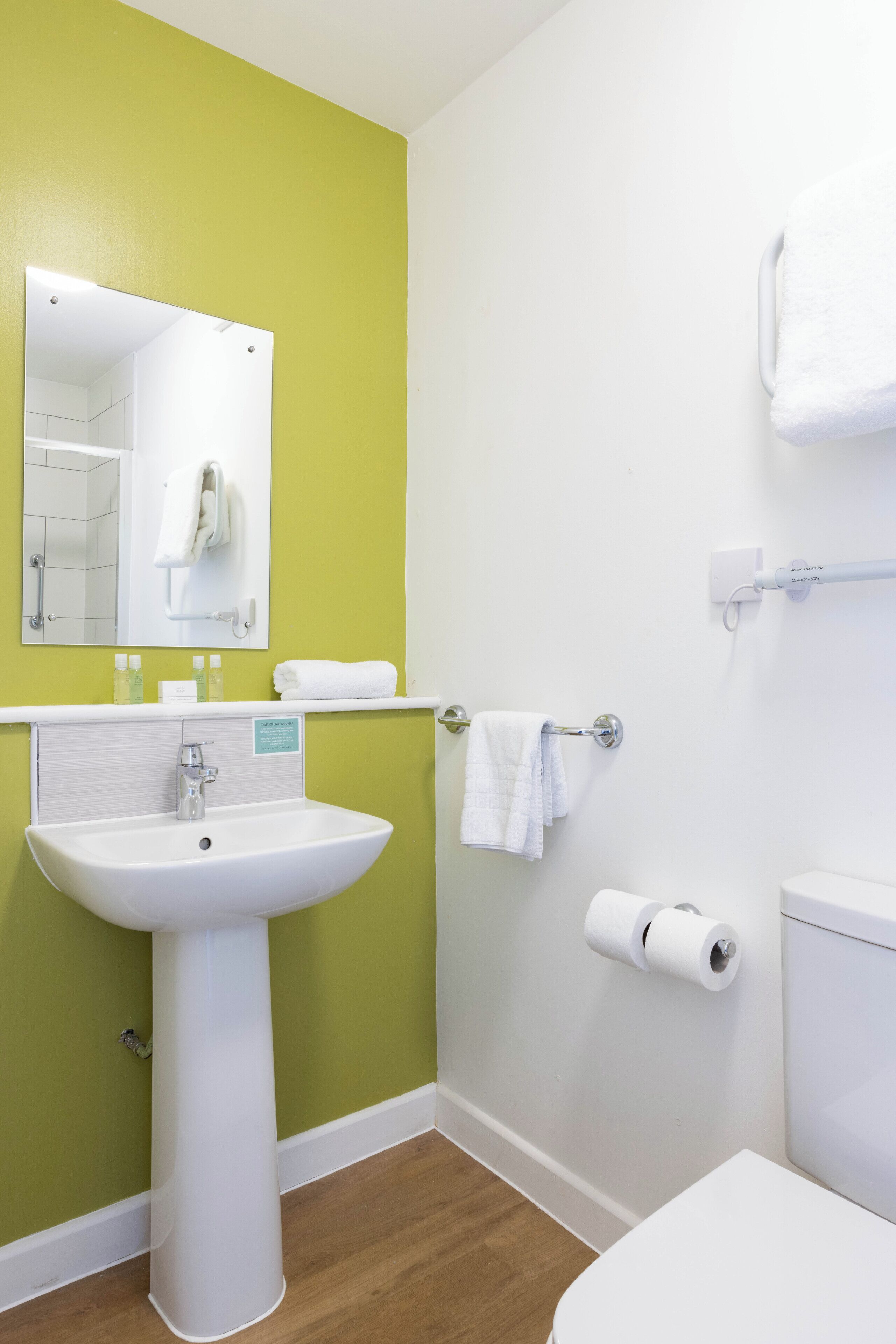A bathroom with a white sink, toilet, and a mirror.